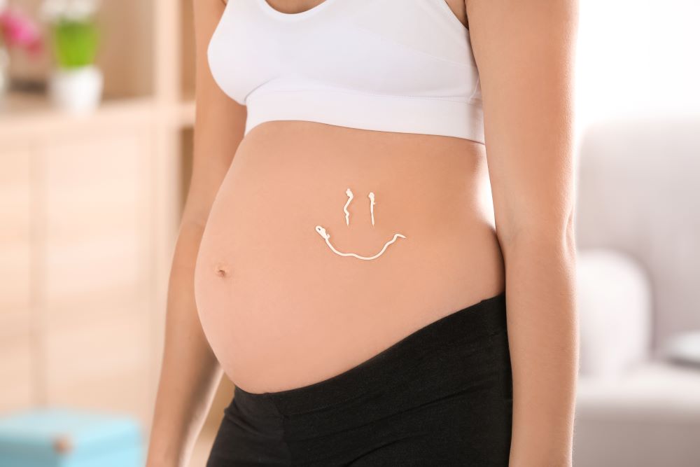 femme enceinte avec un coeur en crème sur le ventre